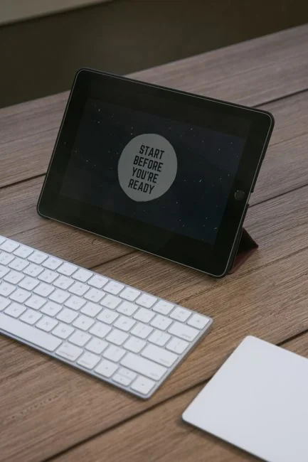 Business professional using a tablet and laptop with a hot drink, focusing on digital content review.